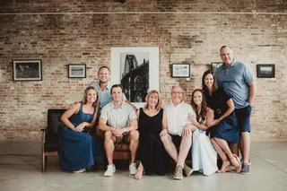 A smaller group sits together on a couch in front of a brick wall.