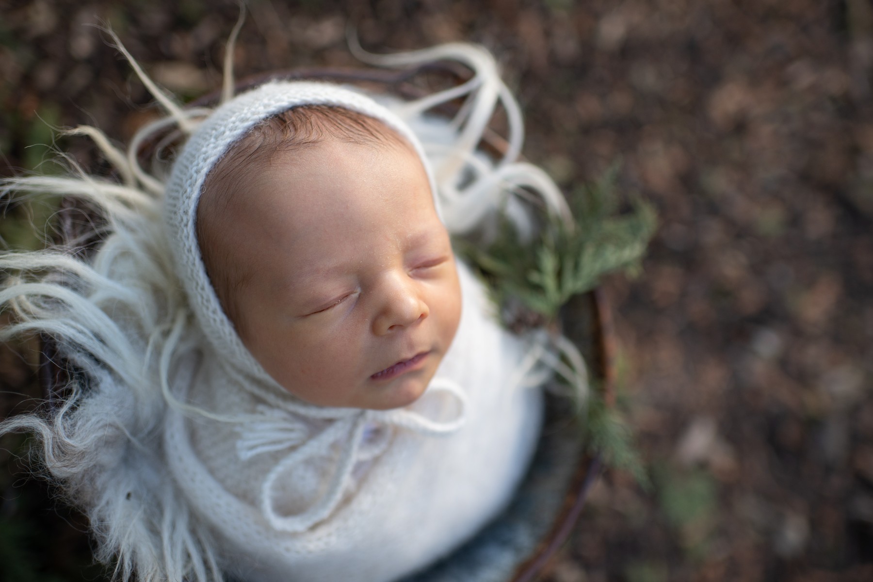 Before: Newborn resting in a soft outdoor nest.