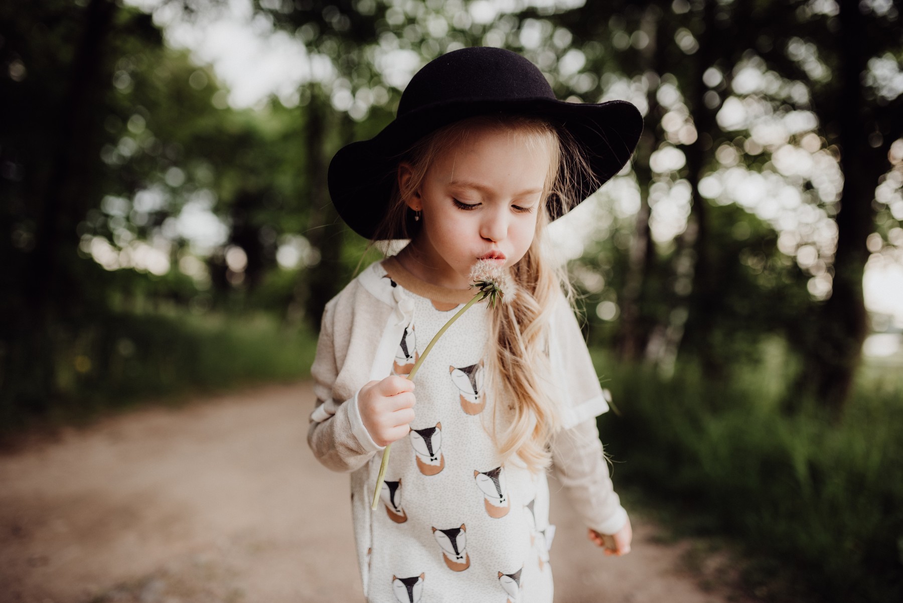 After: Girl in a hat blowing a dandelion.