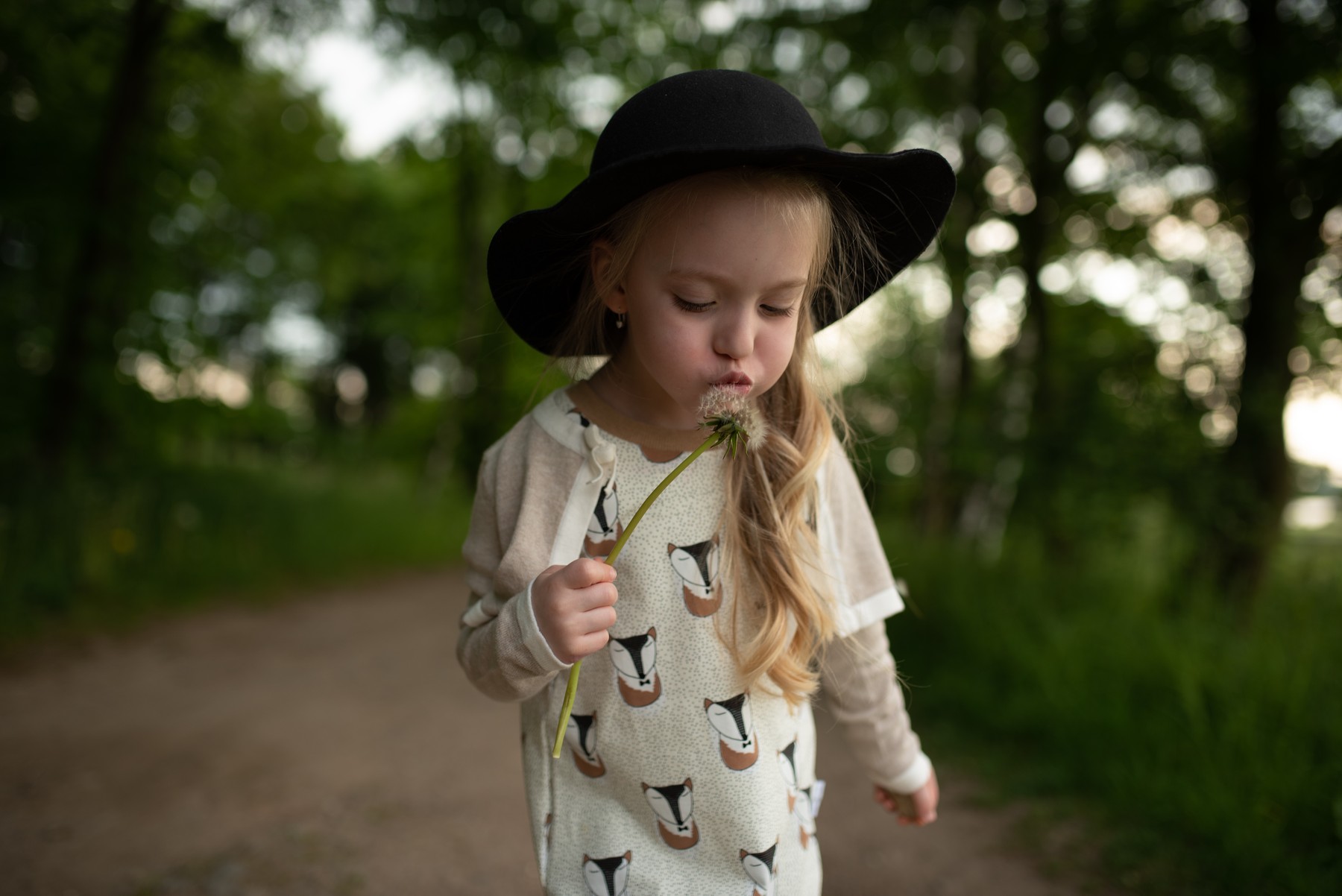 Before: Girl in a hat blowing a dandelion.
