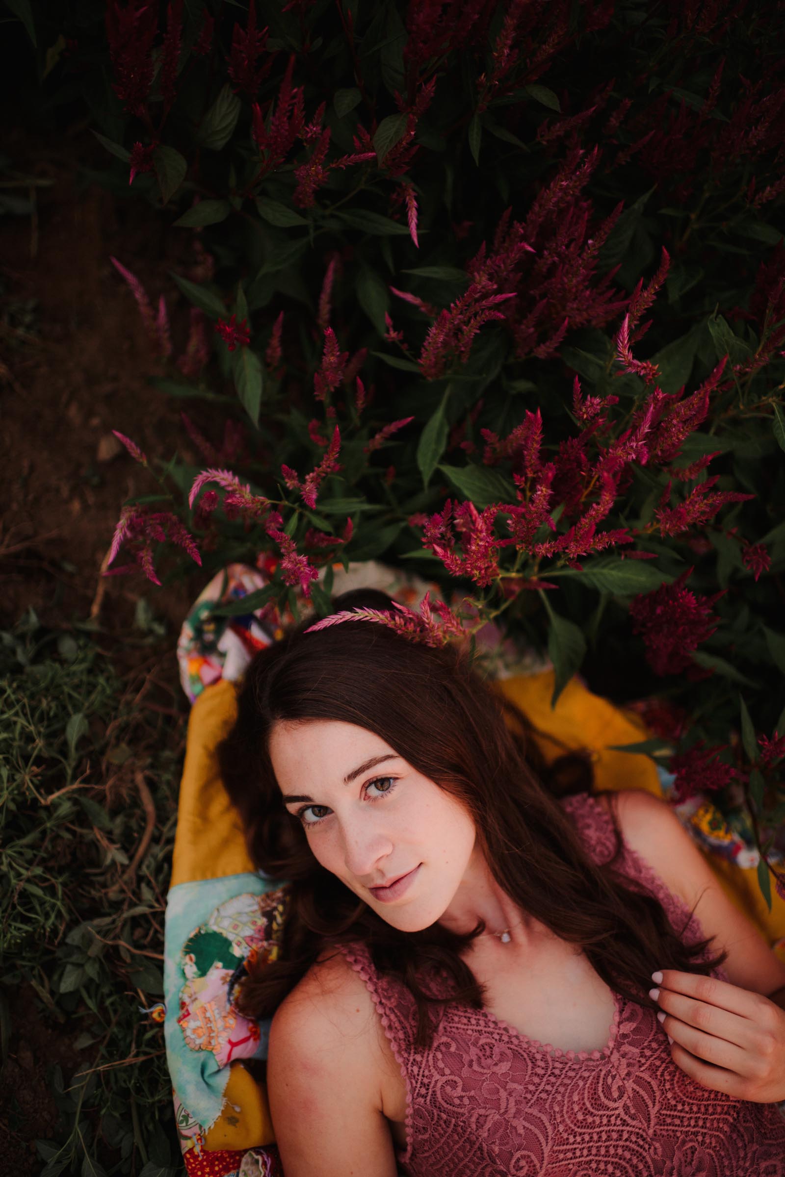 senior girl laying in field by flowers