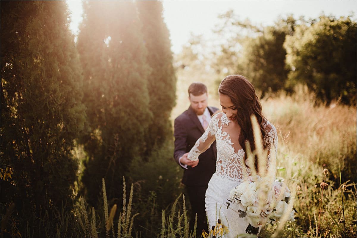 Bride Leading Groom Through Grass