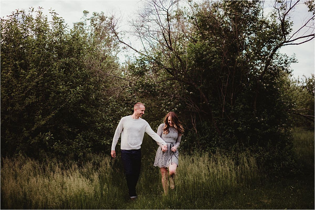 Moody Skies Spring Engagement Session Couple Holding Hands in Field