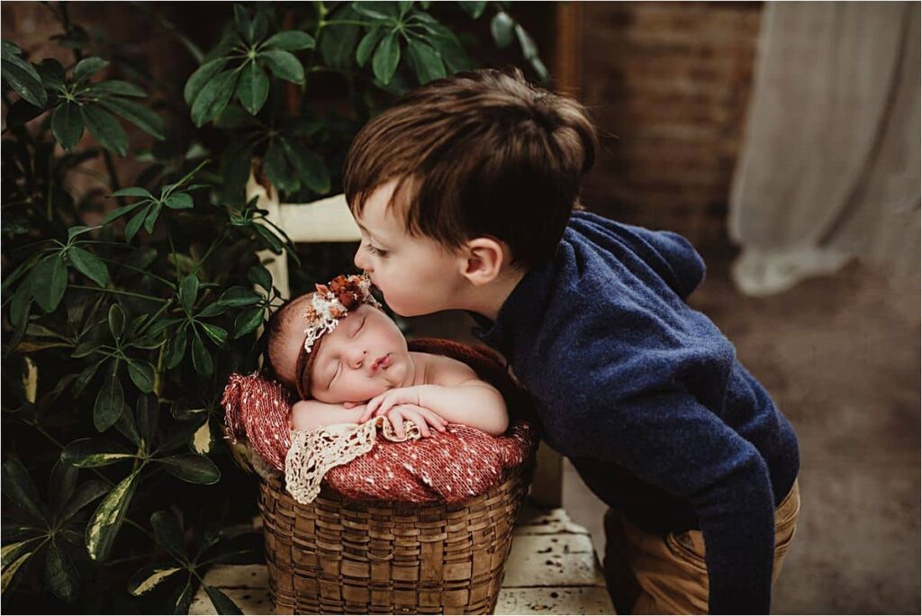 Jewel Tones Newborn Session Brother Kissing Newborn Sister