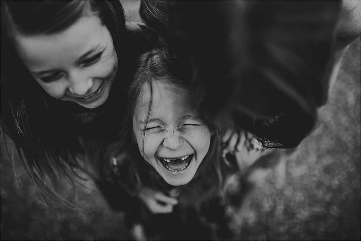 Black and white close-up of two girls laughing together during a candid family session