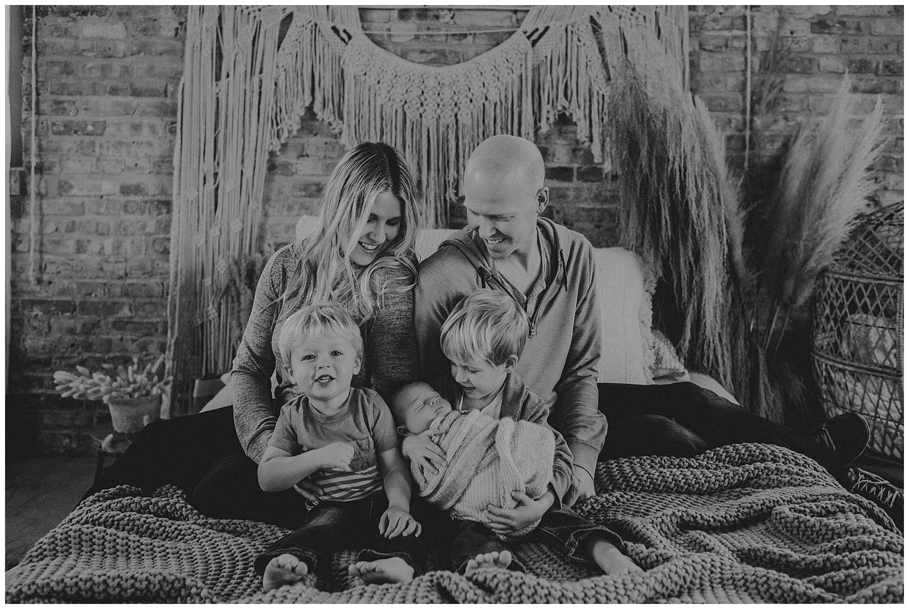 Parents sitting with their three young sons, including a newborn, in the studio.