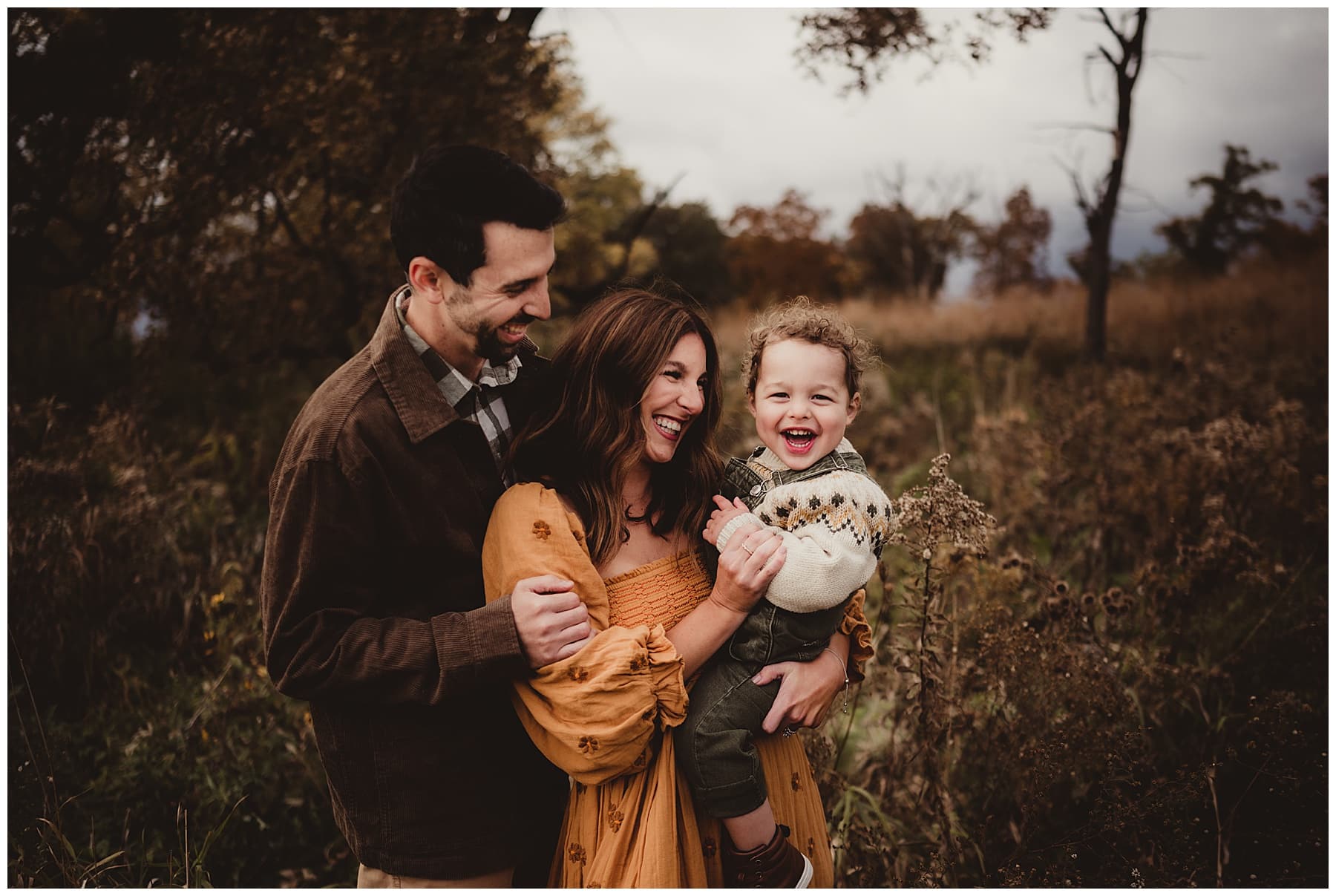 Parents laugh with their toddler in a meadow at Cherokee Marsh.