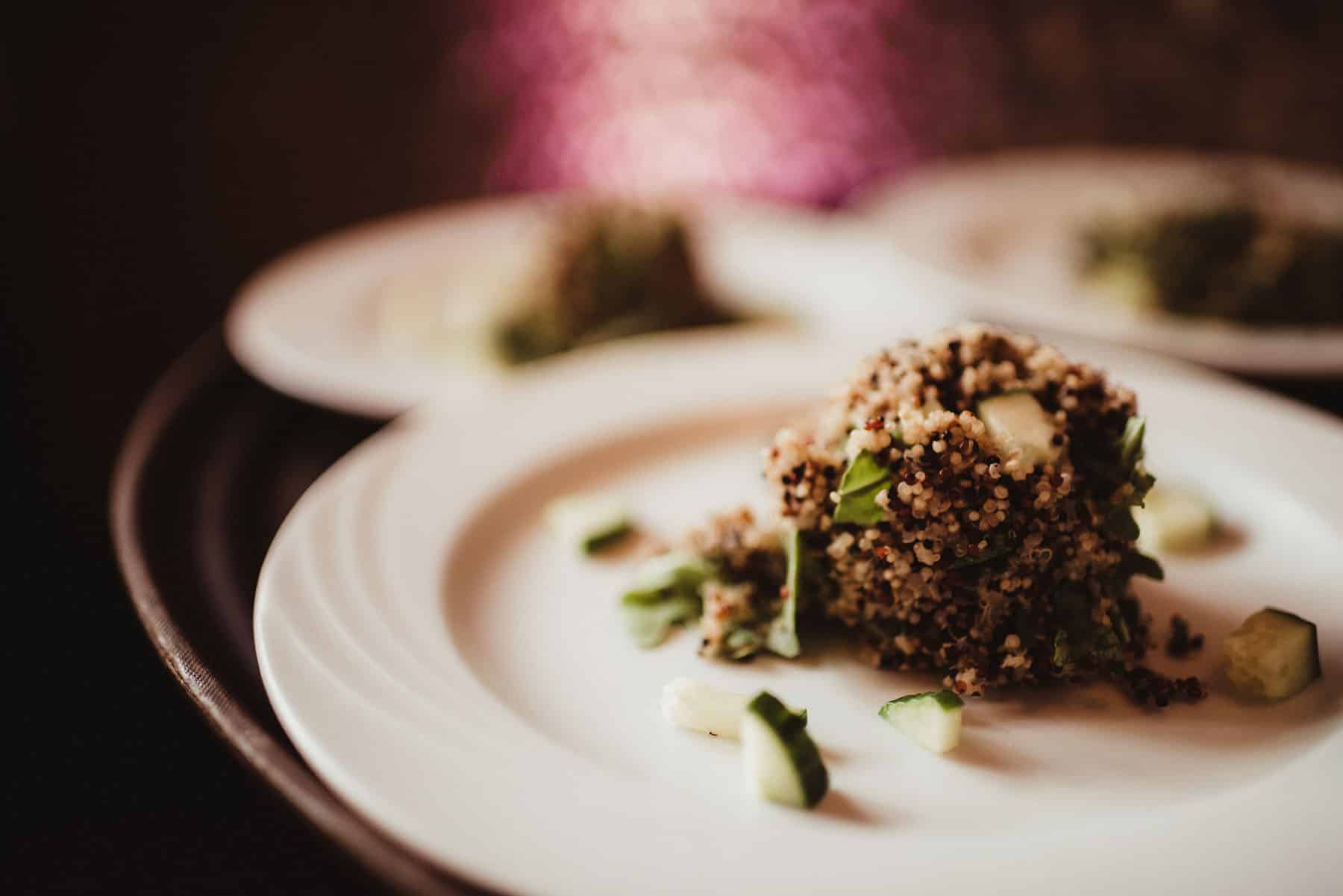 Exquisite gourmet quinoa salad served on a white plate, garnished with greens and diced cucumbers