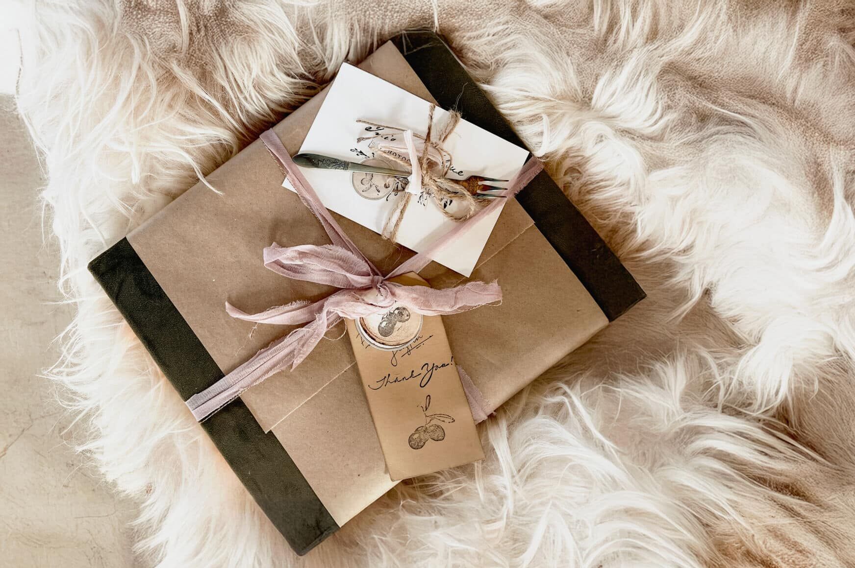 Two beautifully wrapped gift packages with pink ribbons and vintage-style thank you tags, placed on a soft, textured furry surface.