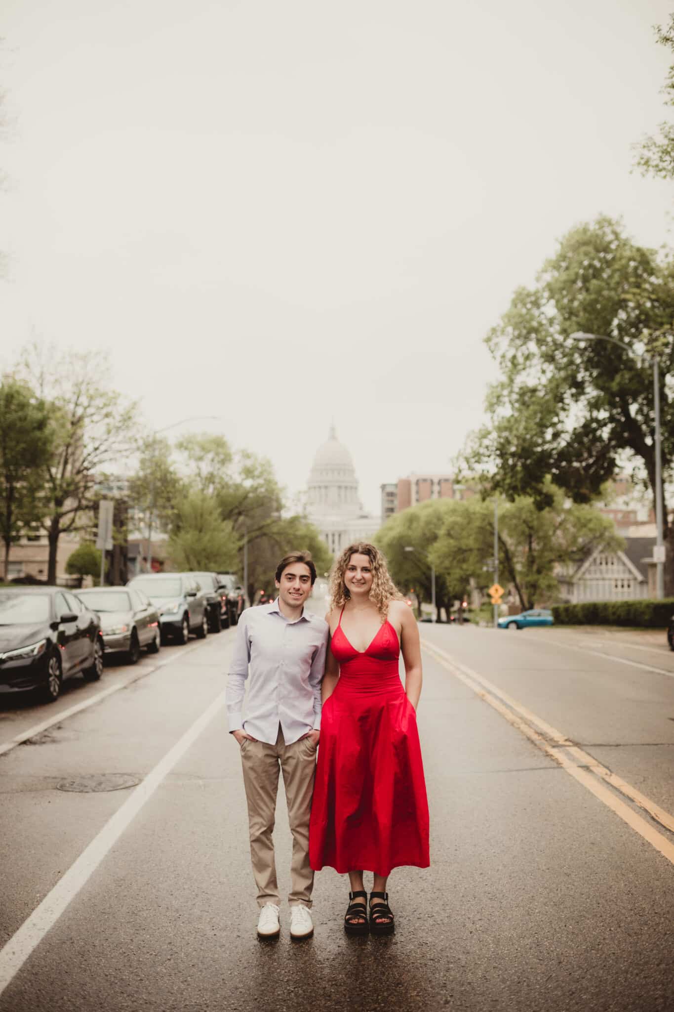 couple_walking_city_street_dressed_up Young man in a dress shirt and woman in a red dress walking on a city street with a blurred capitol building in the background