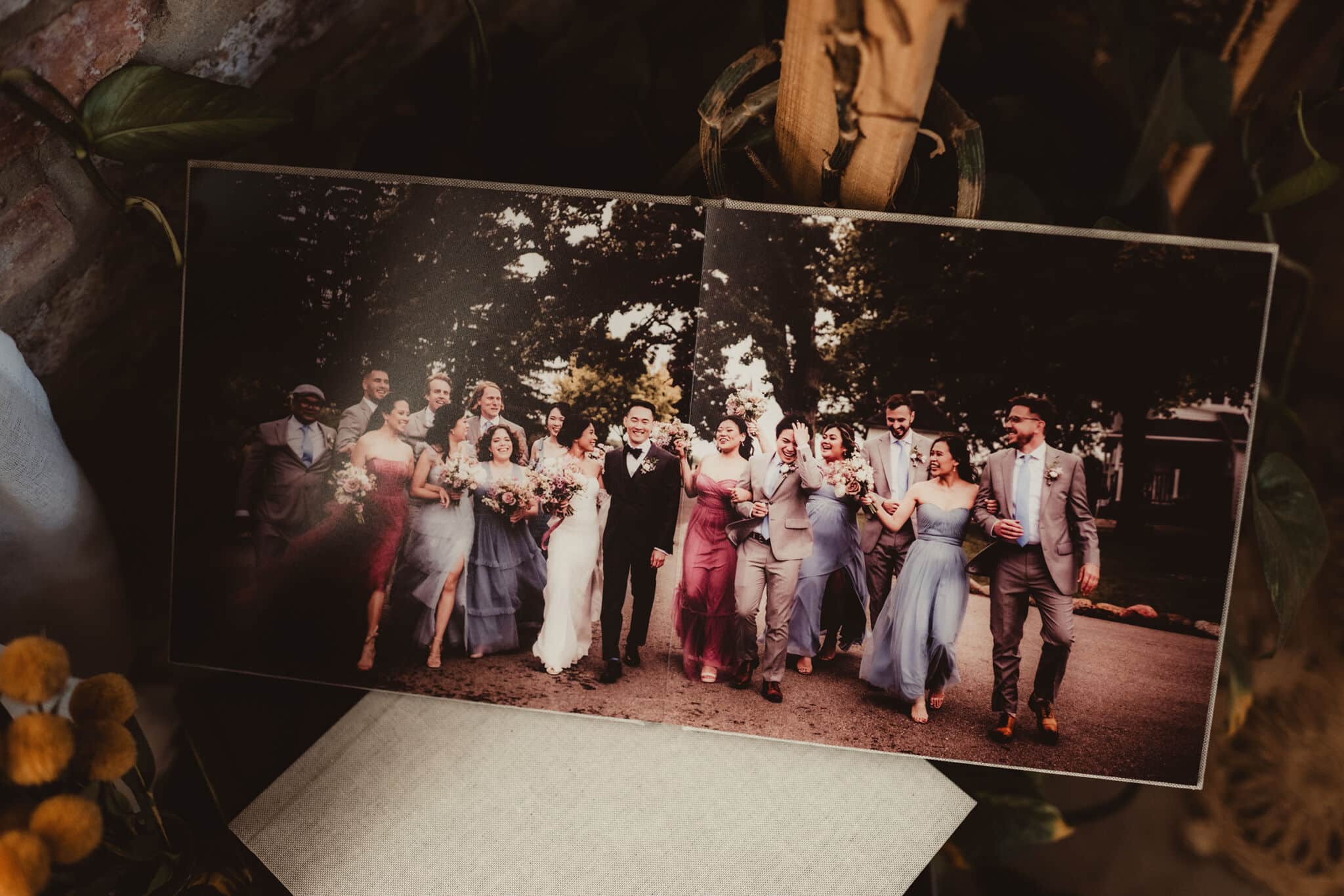 Open wedding album with one panoramic wedding-party photograph across both pages