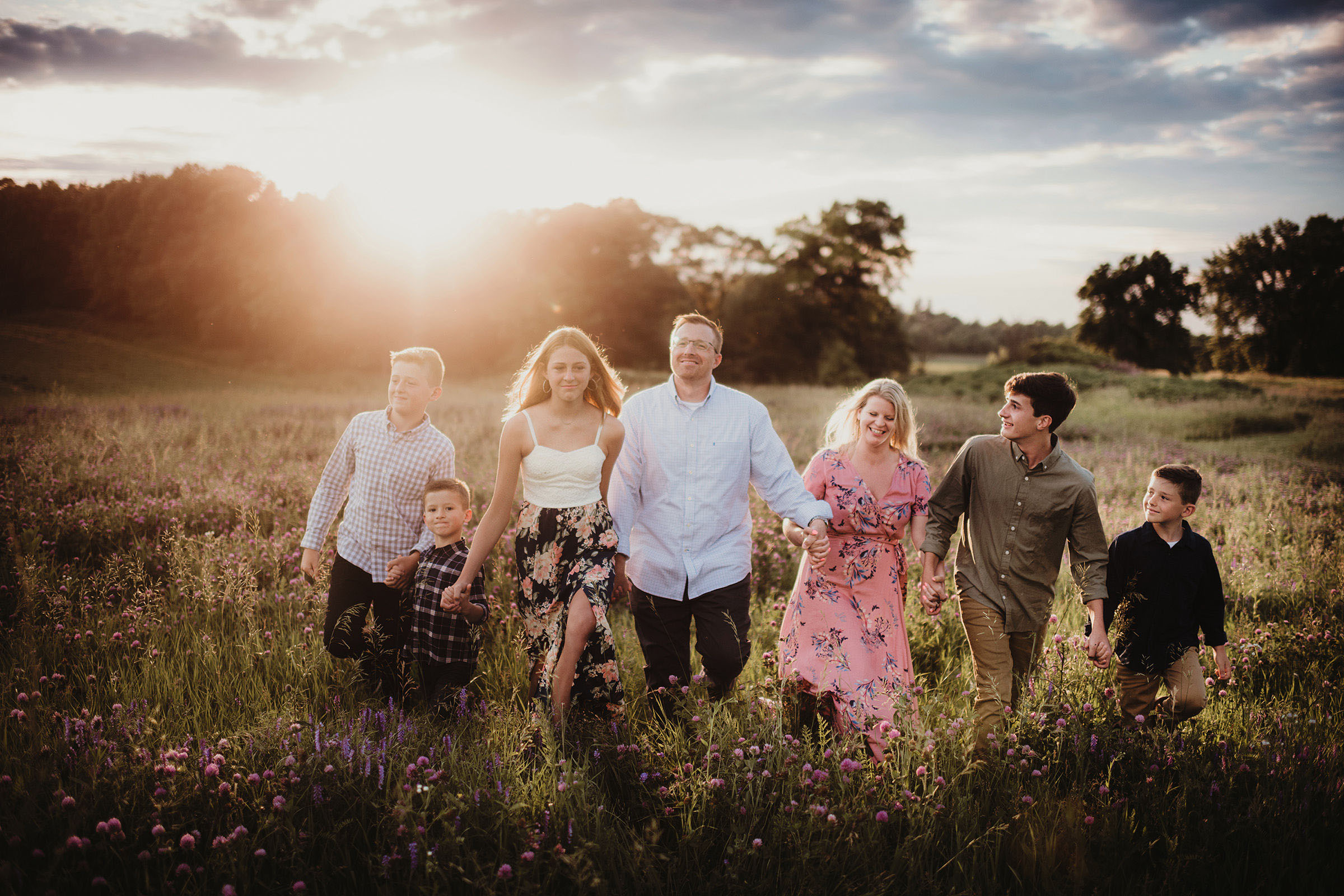 Family standing together in a wildflower meadow at golden hour