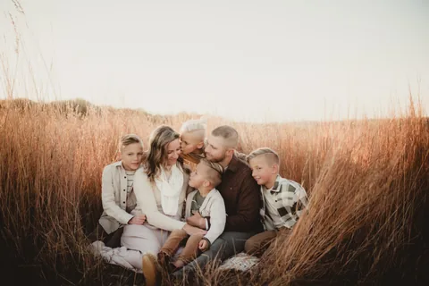 A family sits close together in a field of tall grass.