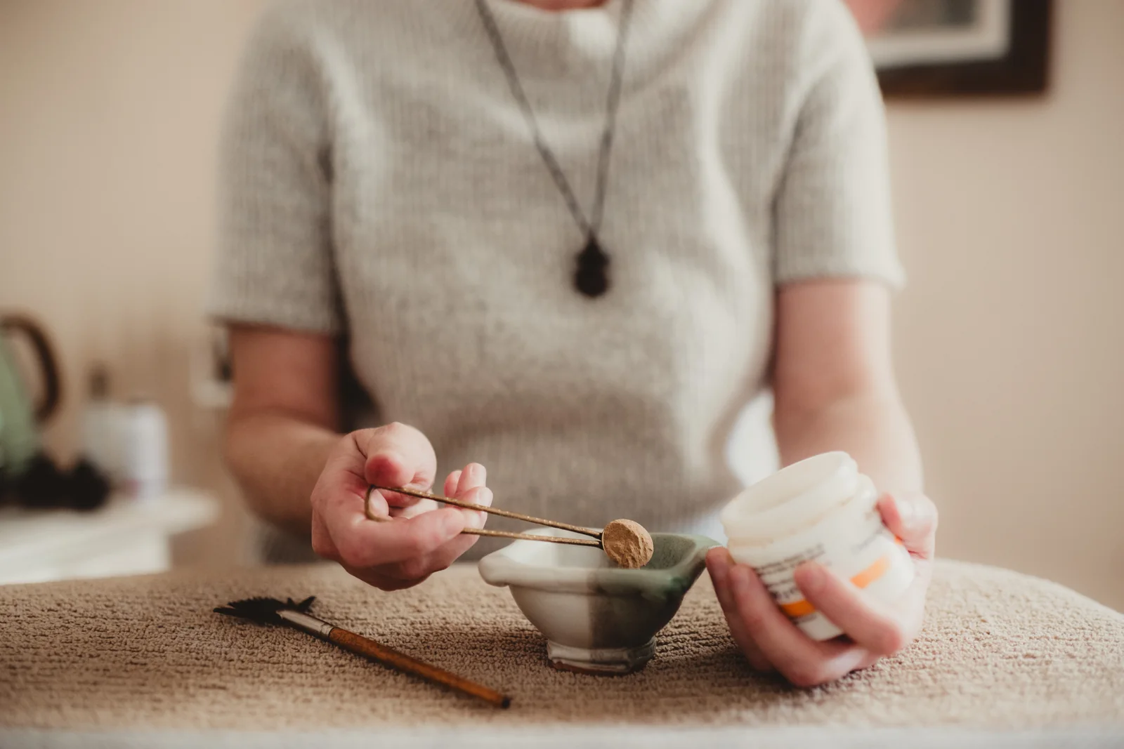 Hands measure powder into a small bowl during service preparation.