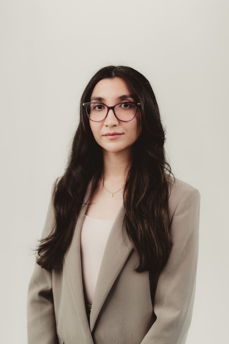 Custom headshot with a cream backdrop Portrait in a light jacket and glasses against a cream backdrop
