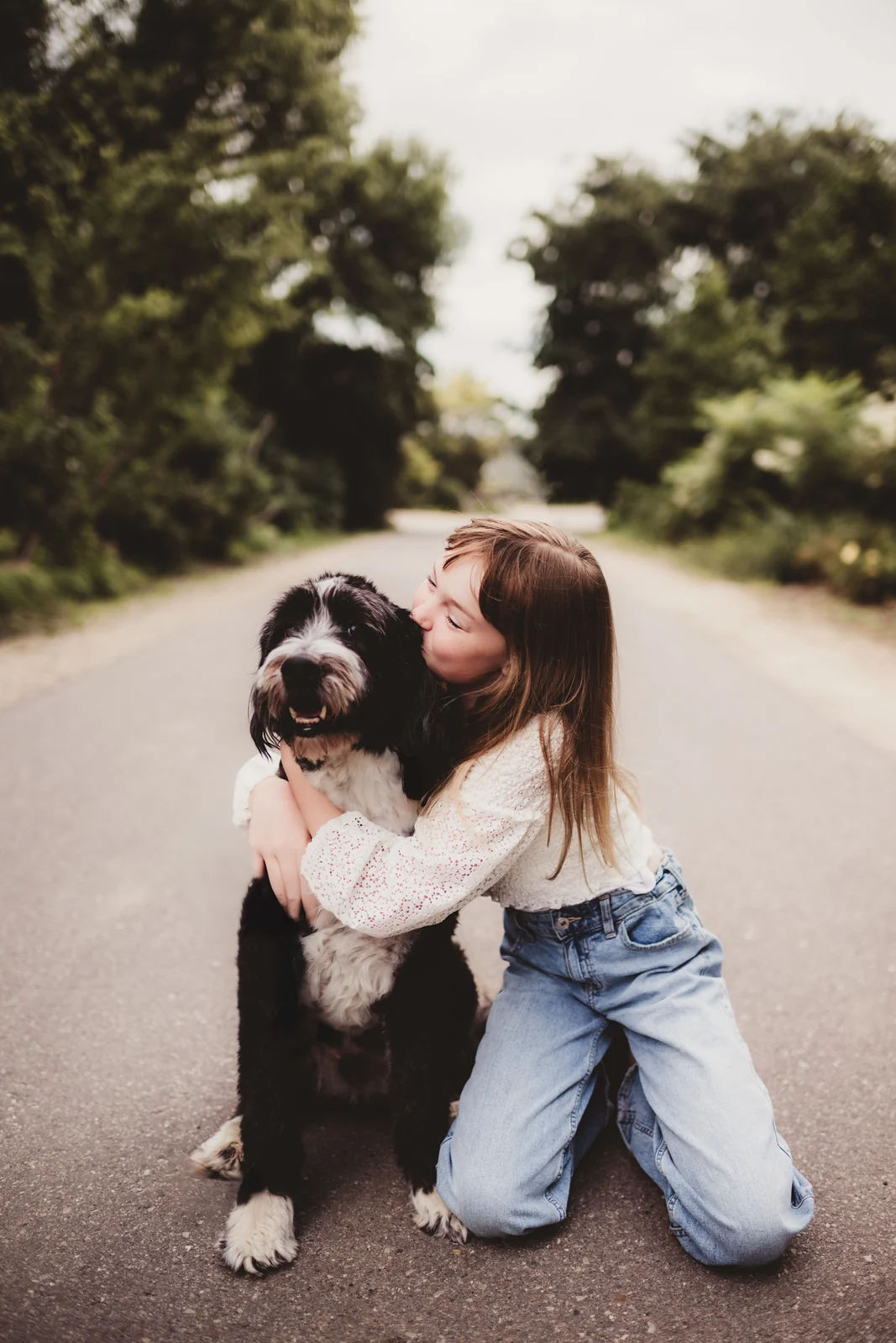 Child hugging family dog A child kneeling beside a large dog and hugging its neck.