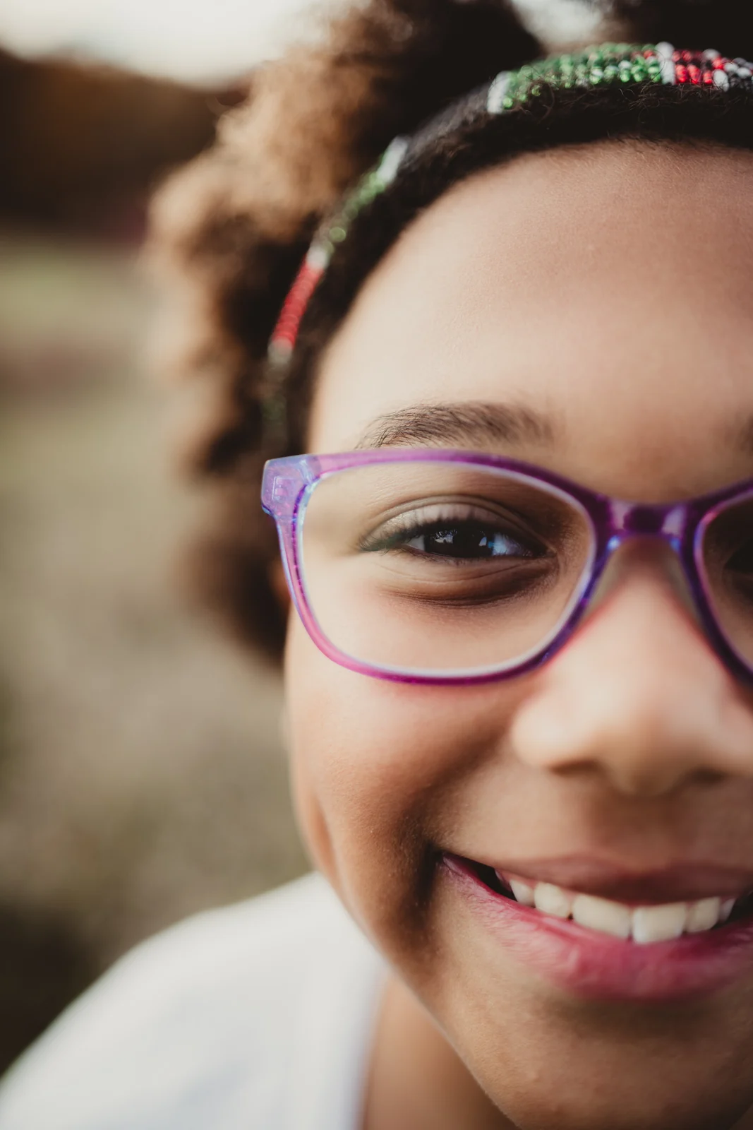 Child with purple glasses A smiling child wearing purple glasses and a flower headband.