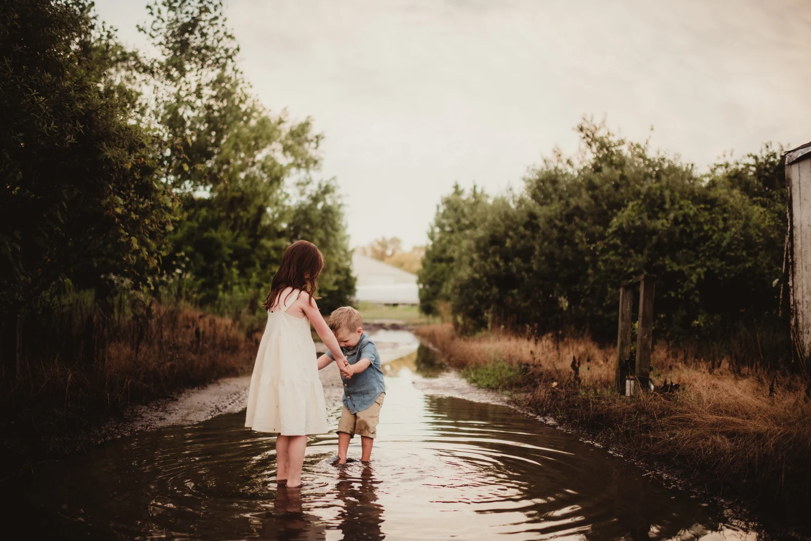 Children wading together Two children holding hands while playing in a shallow puddle.