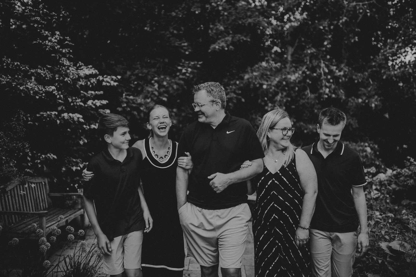 Family black and white garden portrait A black and white photograph of a parent surrounded by older children in a garden.