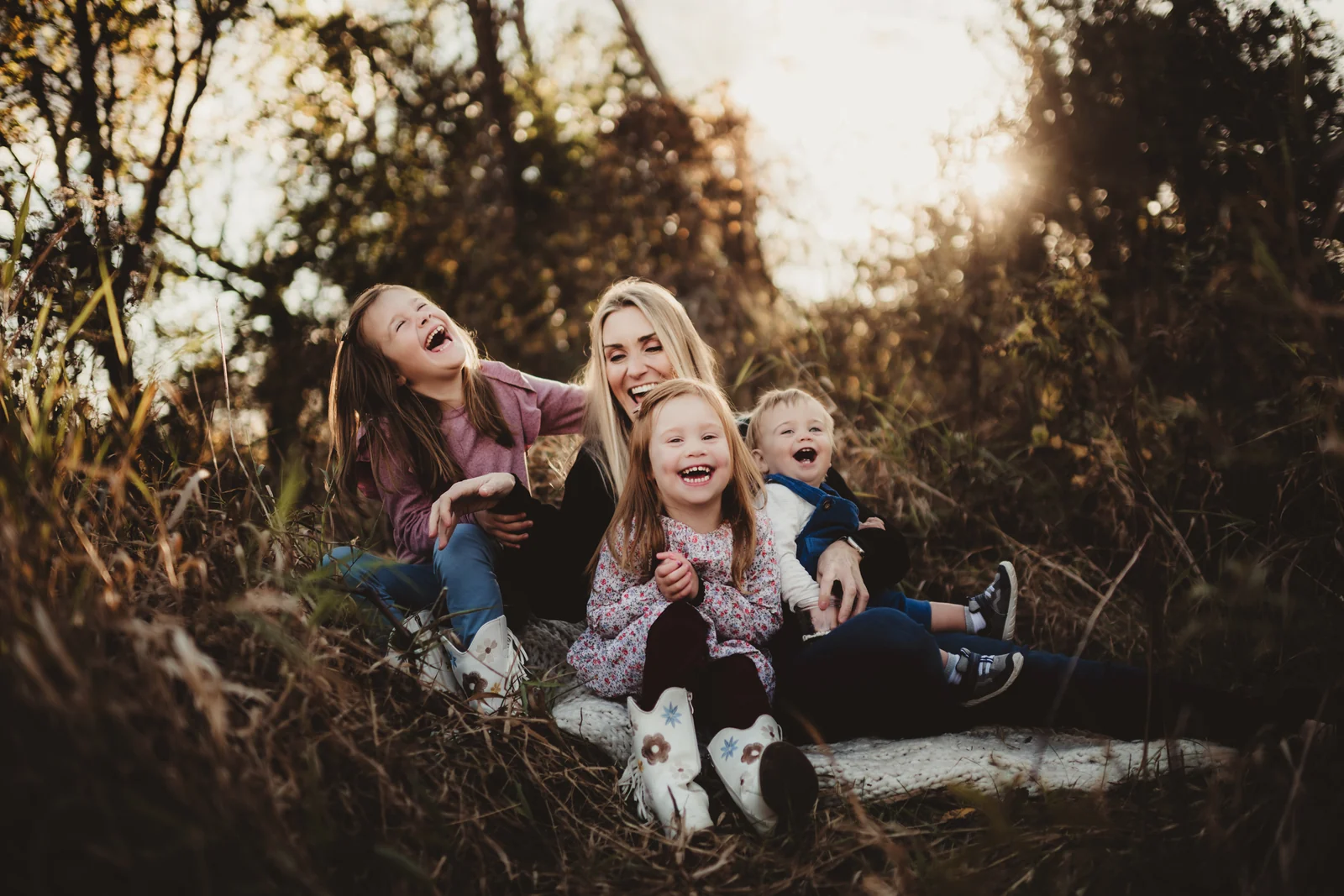 Family laughing on a stone wall A family leaning together and laughing while seated on a low stone wall.