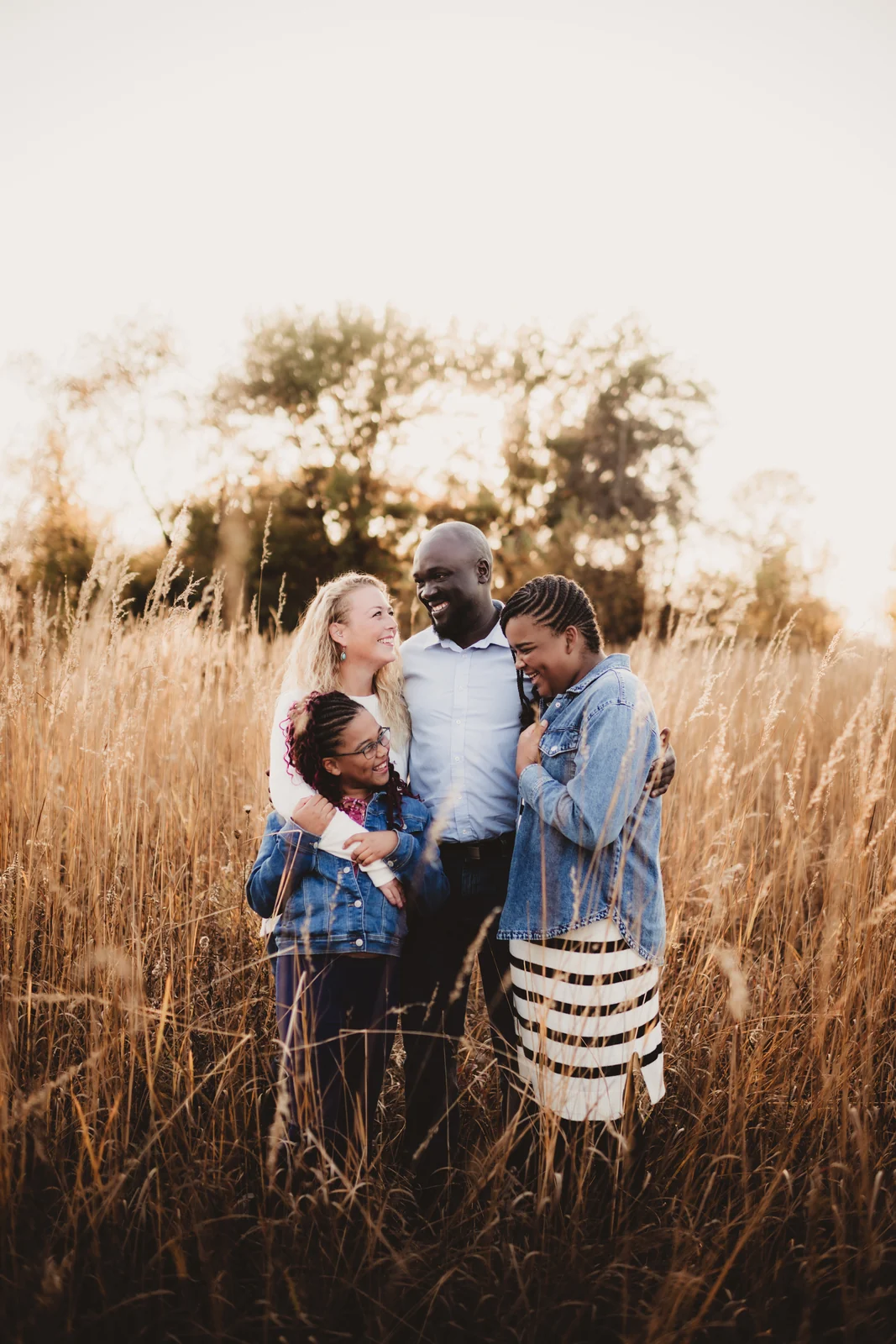 Family portrait in tall grass A family of four standing close together in tall golden grass.