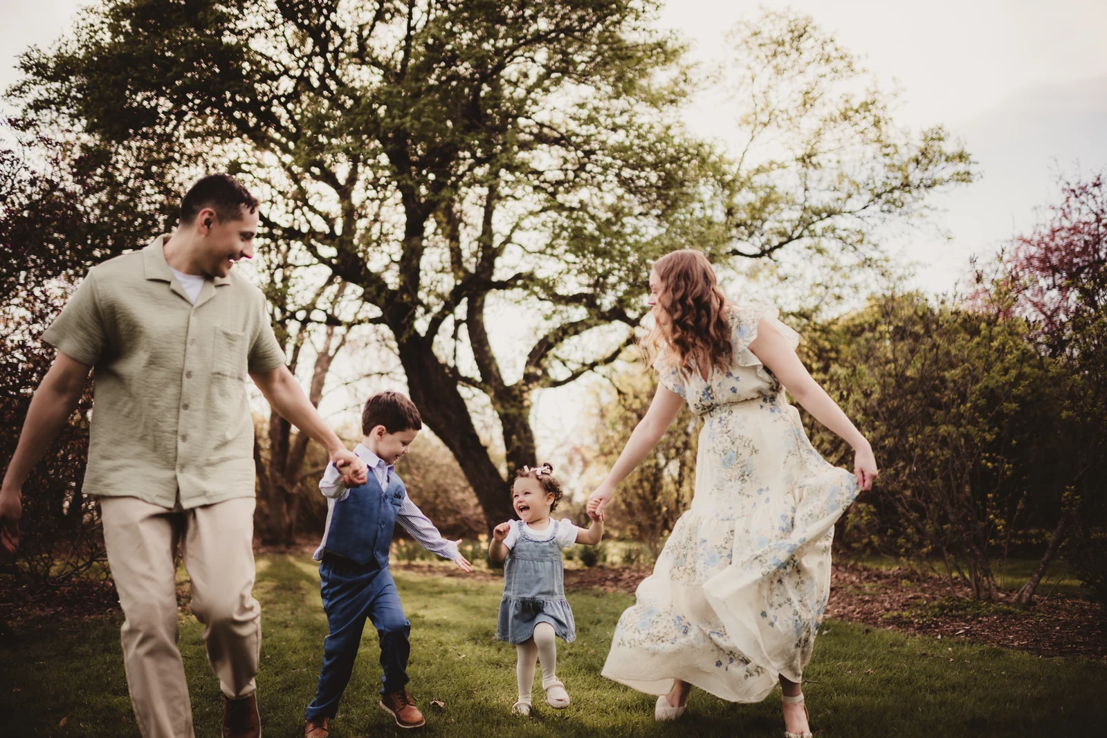 Family walking hand in hand Parents walking hand in hand with their children beneath spring trees.