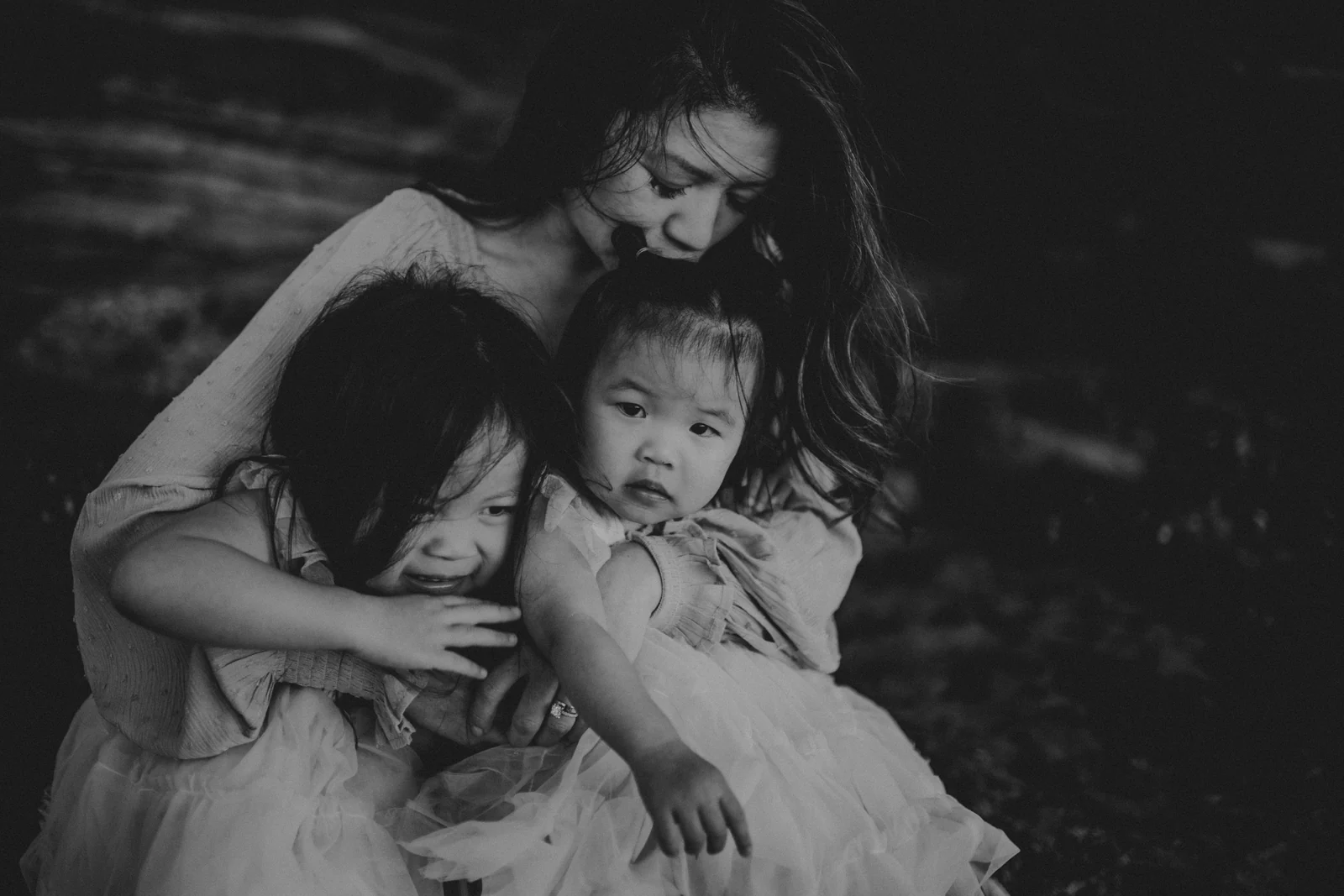 Parent and children black and white A black and white portrait of a parent cuddling two children.