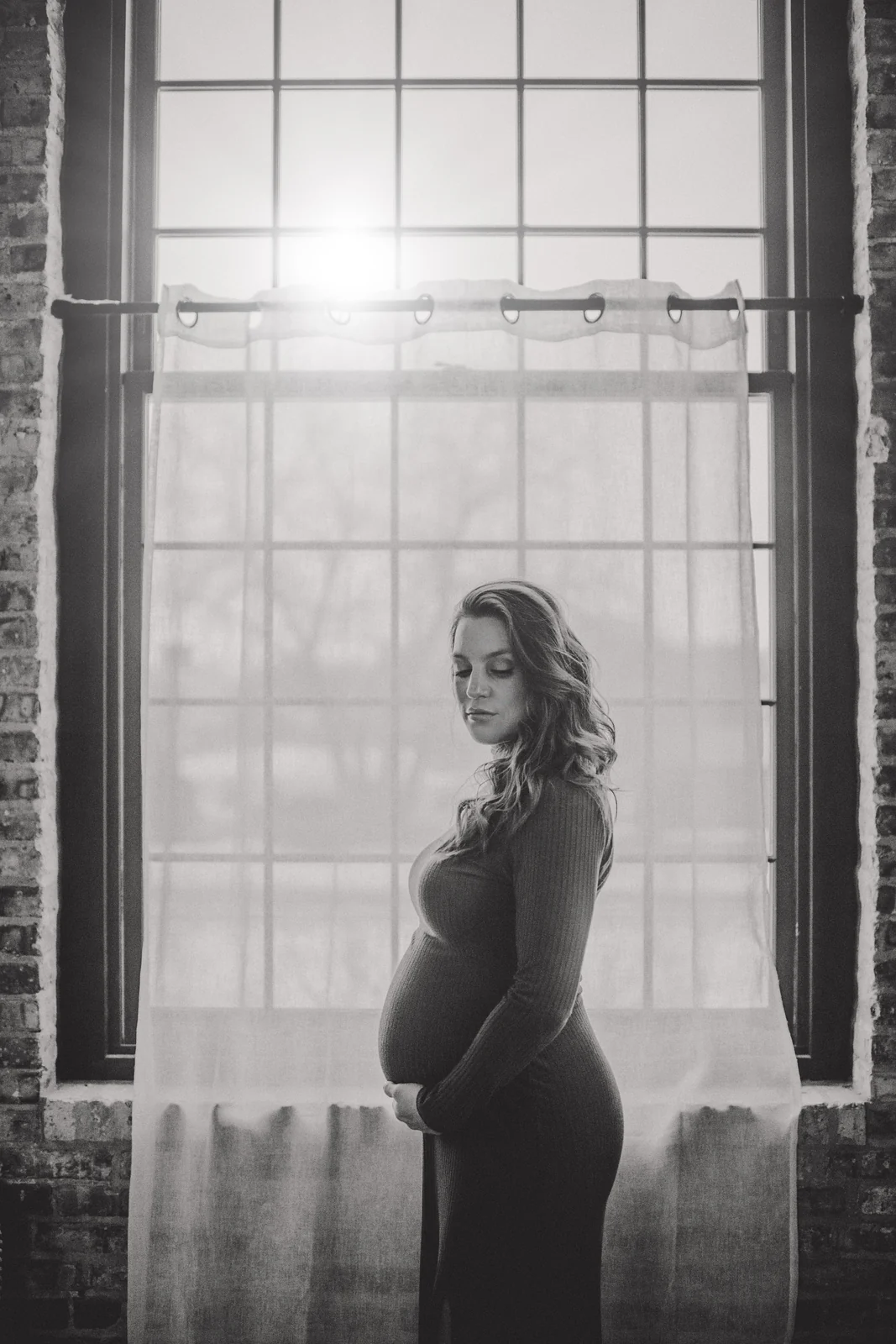 Black and white maternity portrait A black and white maternity portrait beside a tall studio window.