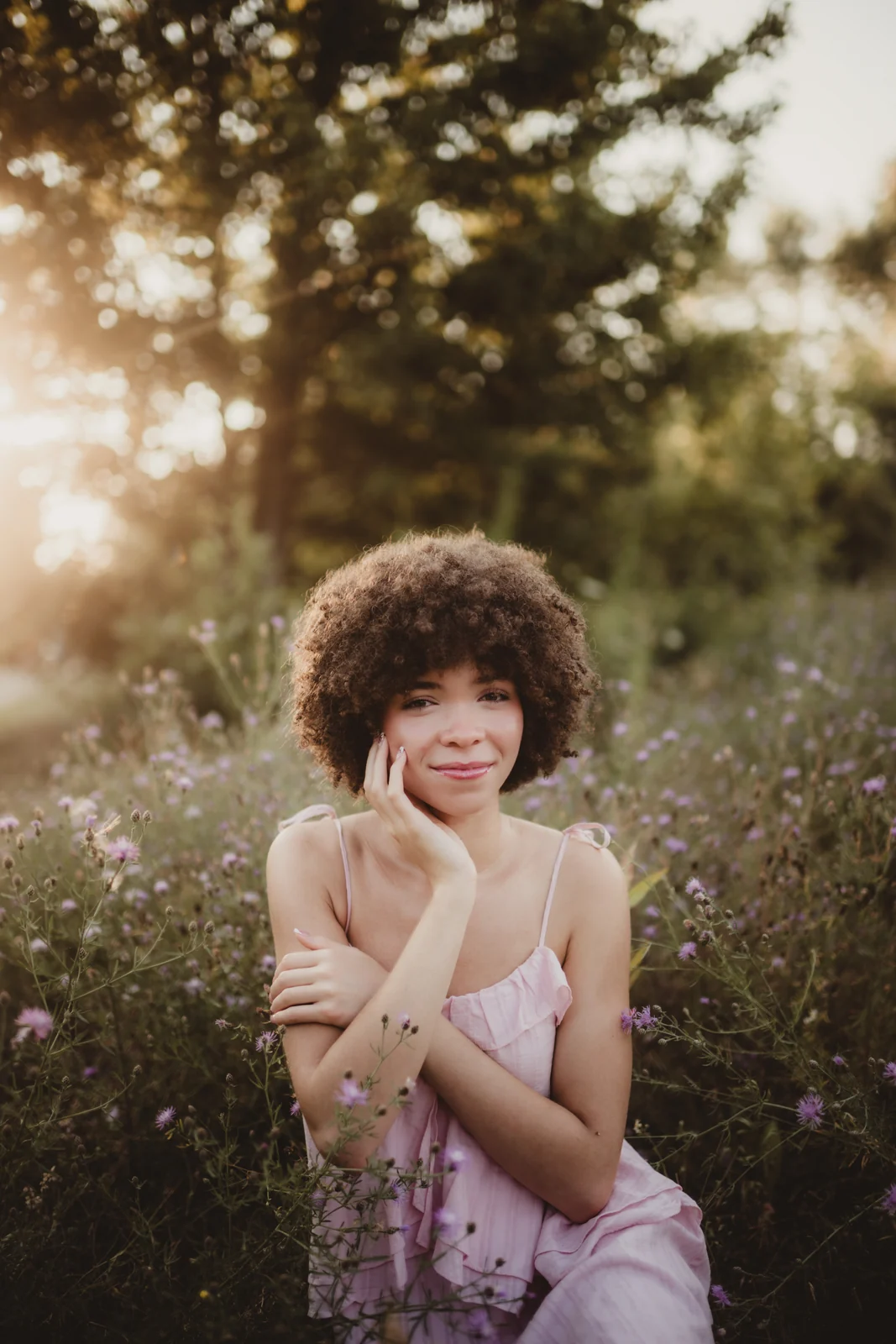 to-senior-2026-senior-among-purple-flowers A senior resting her chin on her hand among purple flowers.