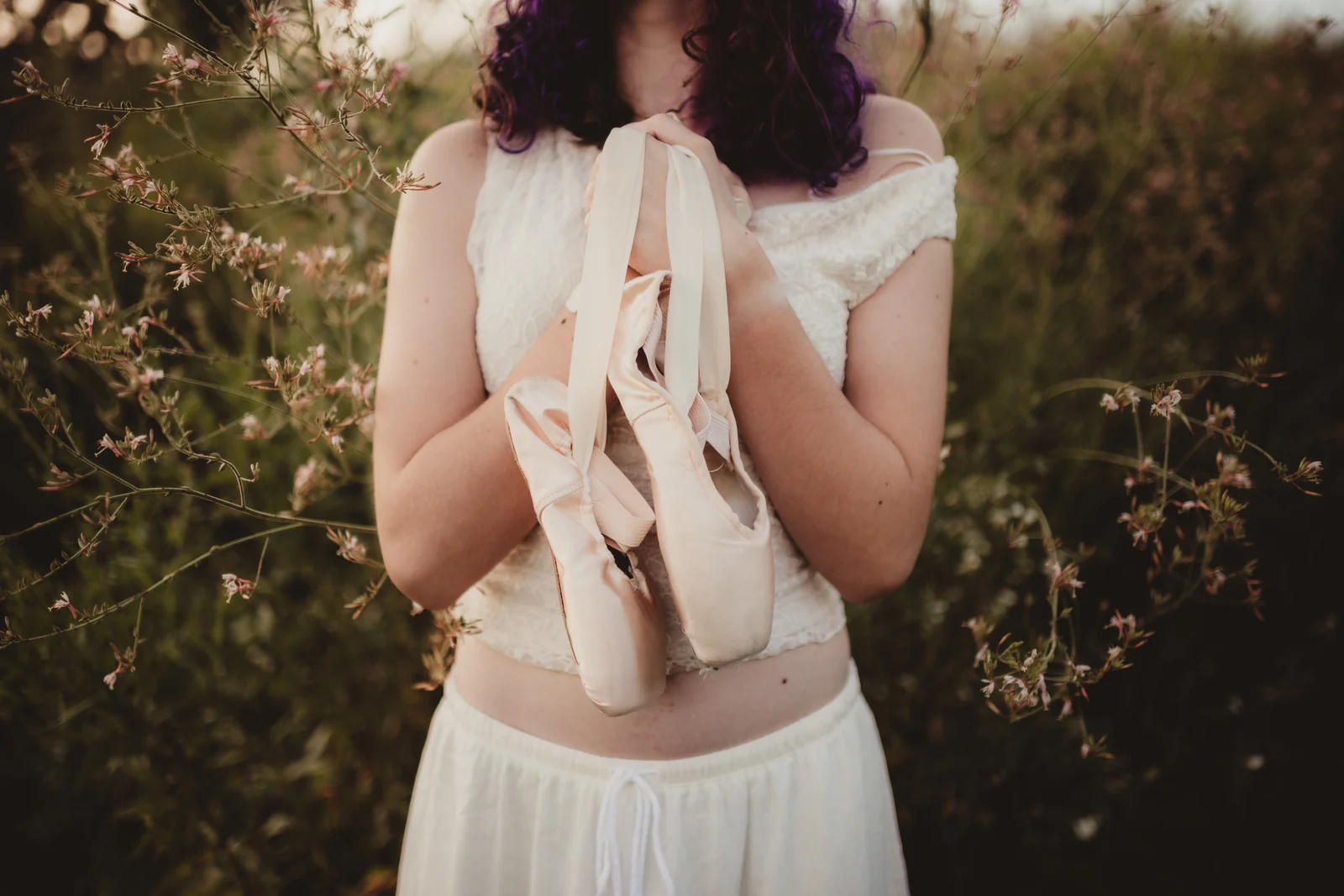 to-senior-2026-senior-ballet-shoes-detail A senior holding ballet shoes with ribbons trailing down.