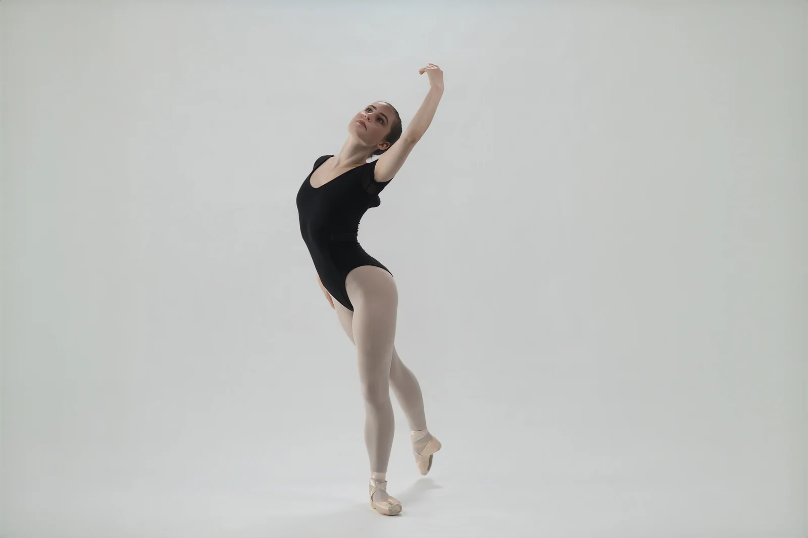 to-senior-2026-senior-ballet-studio A ballet dancer reaching upward during a studio portrait session.