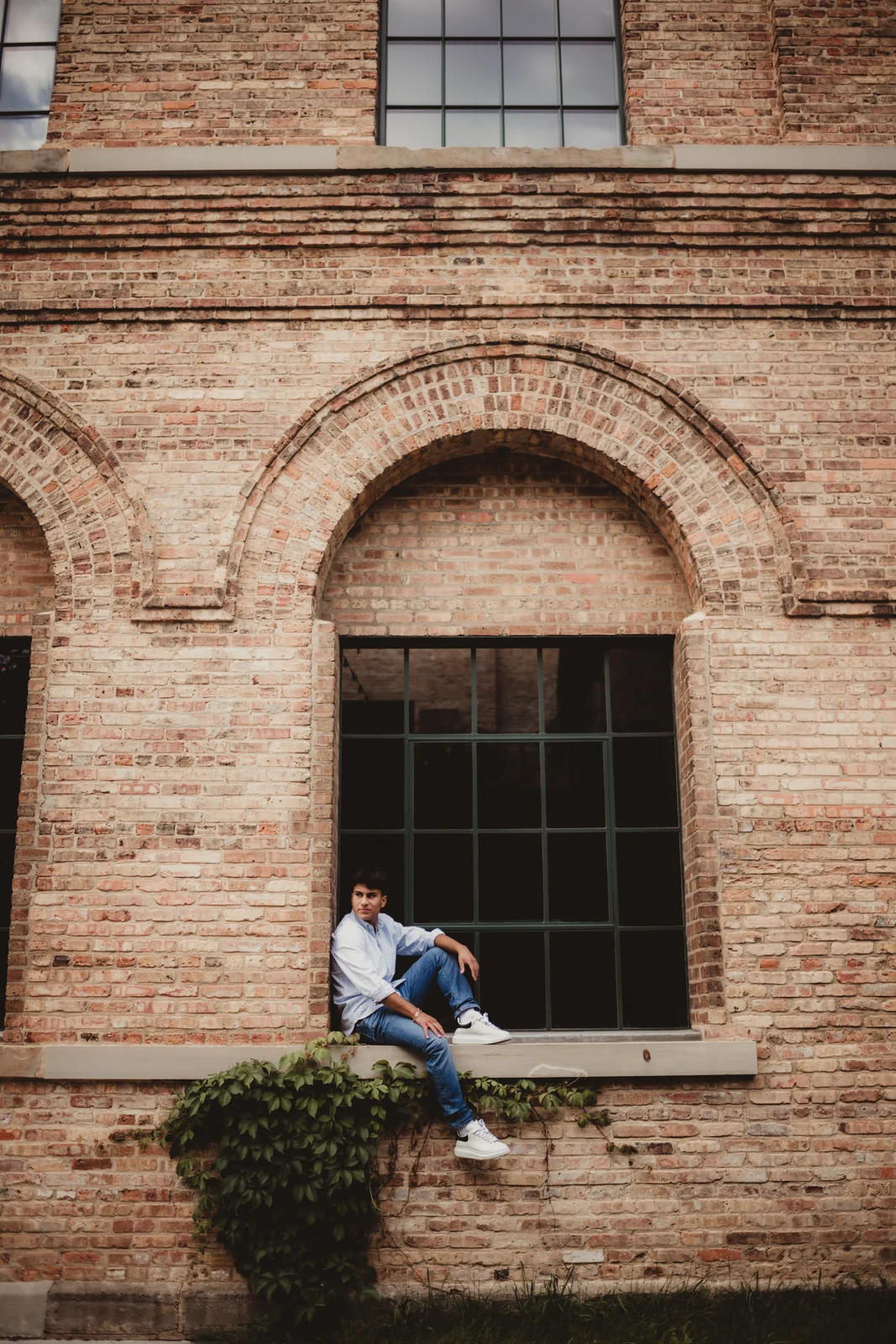 to-senior-2026-senior-brick-window-portrait A senior seated in the window of a tall brick building.