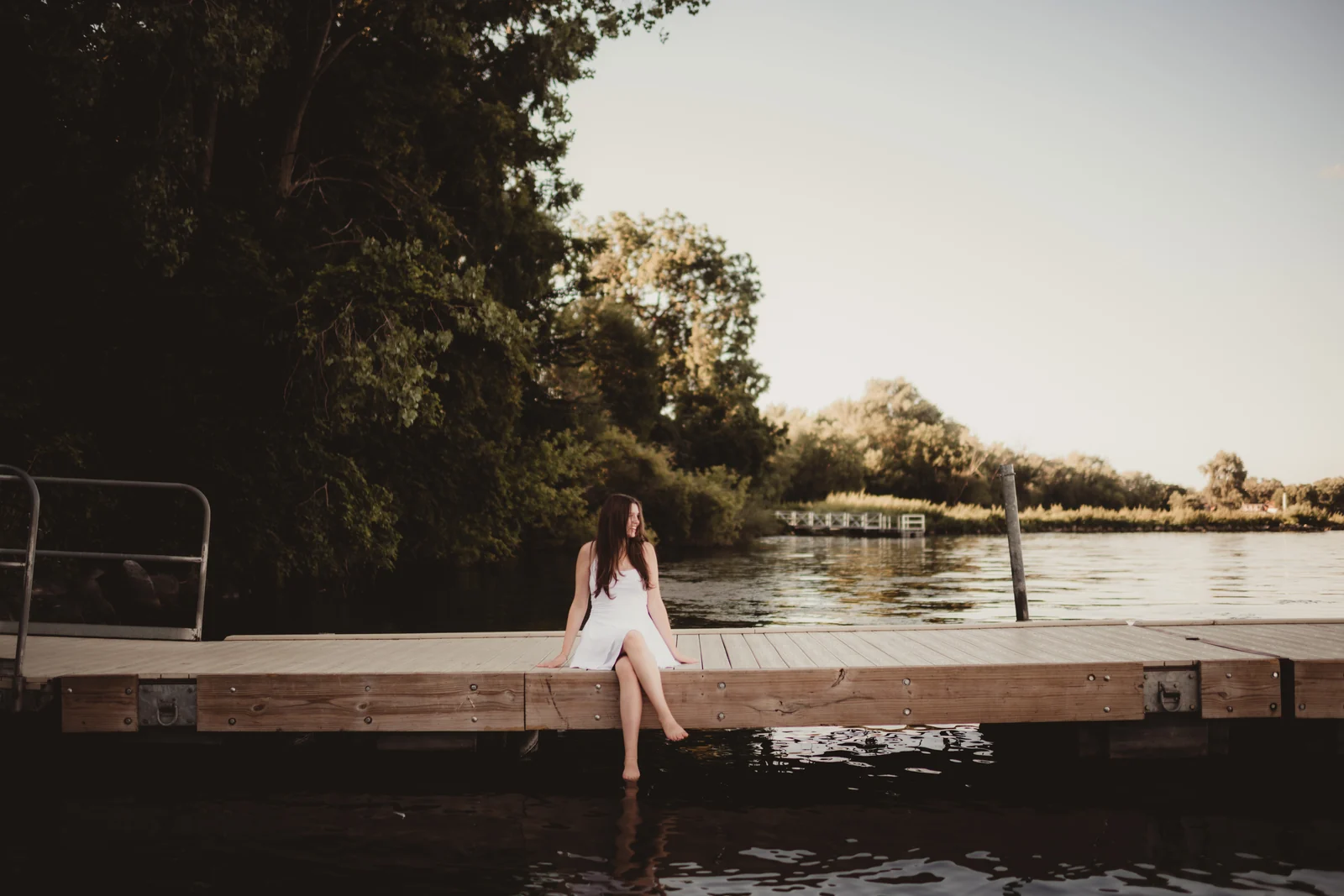 to-senior-2026-senior-seated-on-a-dock A senior seated on a wooden dock overlooking the lake.