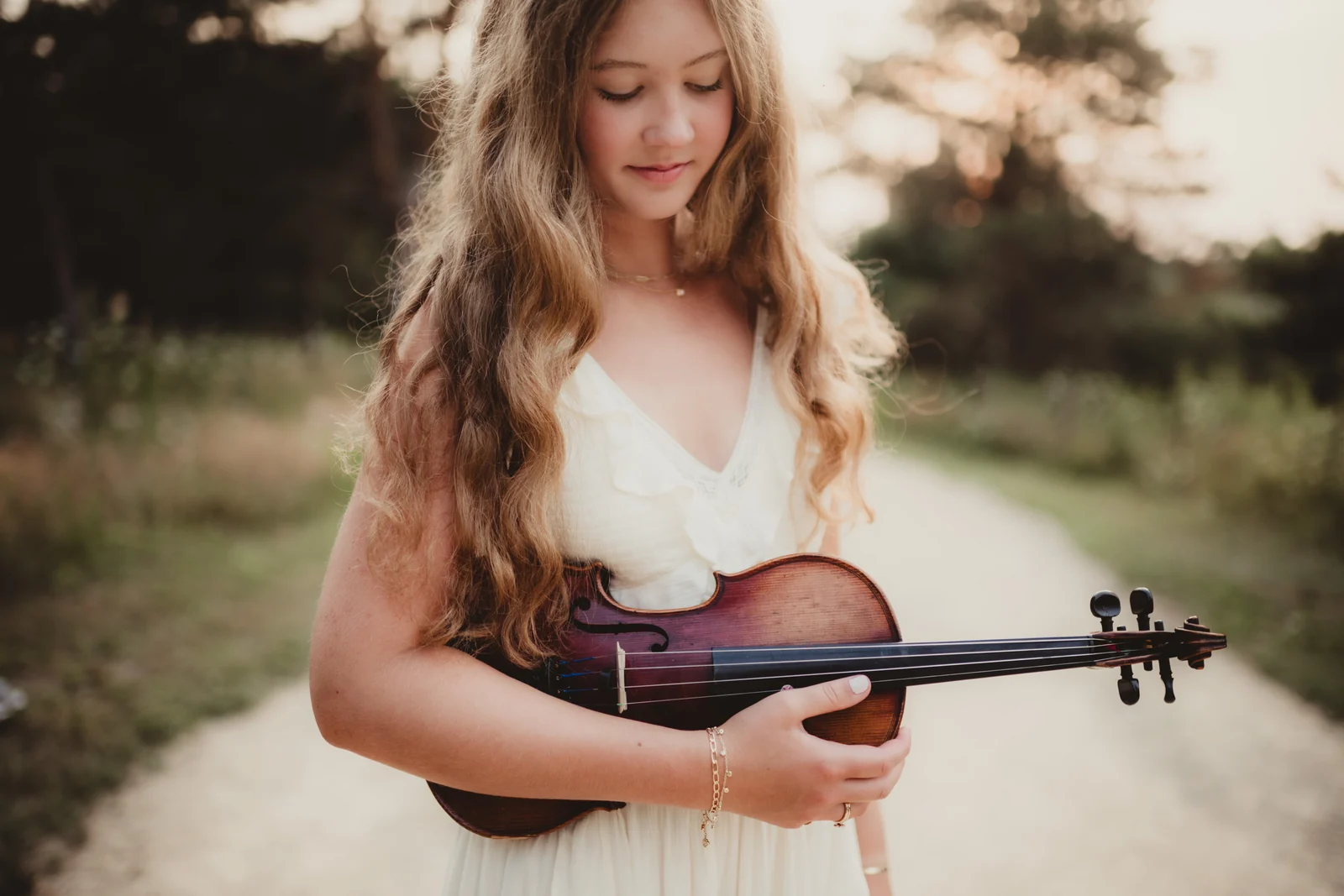 to-senior-2026-senior-with-violin A senior looking down at the violin held in her hands.