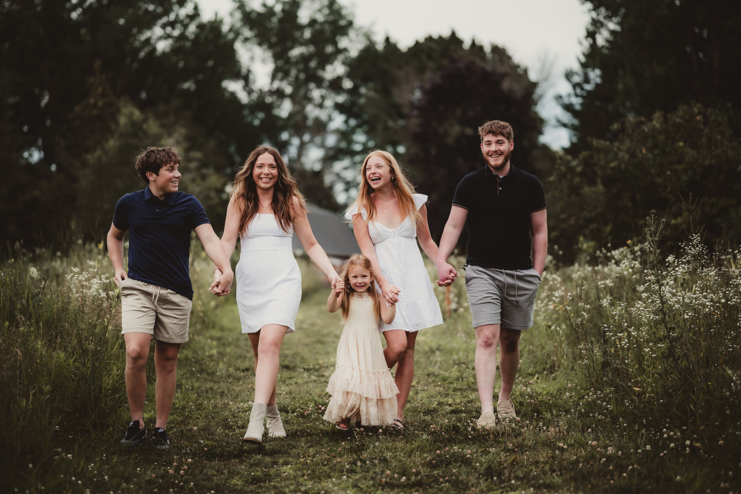 A joyful family walking hand in hand through a lush green field, capturing genuine happiness and togetherness.