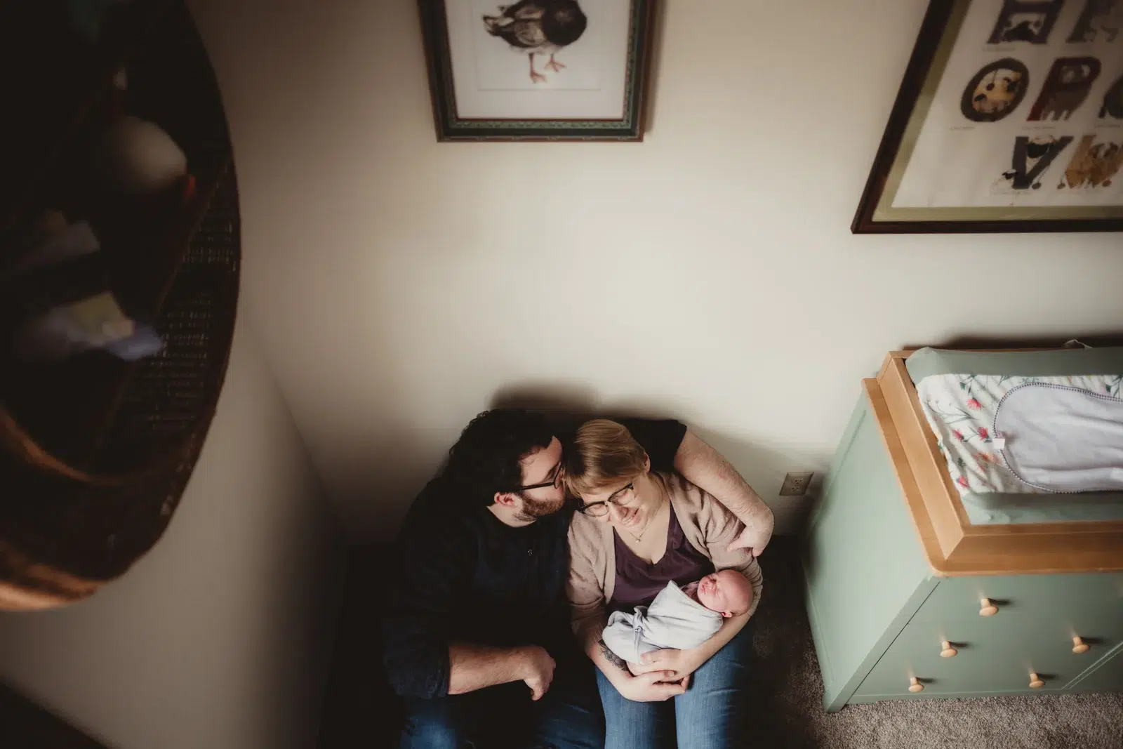 In-home newborn photographs with family in the nursery Parents holding their newborn beside a crib in their nursery.